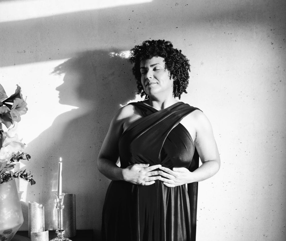 Josefa Nereus steht vor heller Wand im schwarzen Kleid neben ihr Schattenspiel